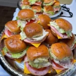 Club sandwich sliders on a platter, garnished with lettuce and tomato