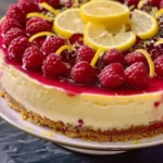 Slice of Lemon Raspberry Cheesecake topped with fresh raspberries and lemon zest