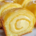 Lemon cream roll cake with a glossy lemon glaze, garnished with lemon zest.