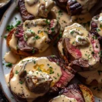 Beef tenderloin crostini topped with creamy parmesan sauce on a platter
