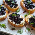 Blueberry Basil Bruschetta topped with fresh basil and blueberries on toasted bread.