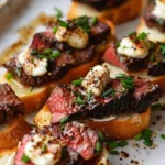 Burrata crostini topped with hanger steak on a rustic wooden board.