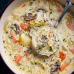 Bowl of creamy artichoke and vegetable soup garnished with herbs