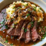 Plate of hearty onion gravy round steak garnished with herbs