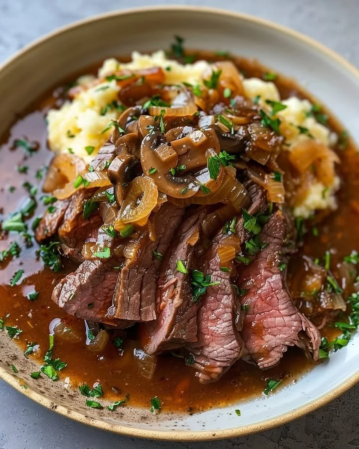 Plate of hearty onion gravy round steak garnished with herbs