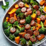 Delicious sheet pan sausage and sweet potatoes meal on a serving dish.