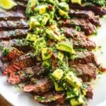Skirt steak with avocado chimichurri garnish on a plate