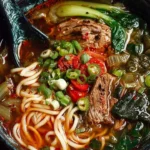 Bowl of spiced steak noodle soup topped with pickled greens.