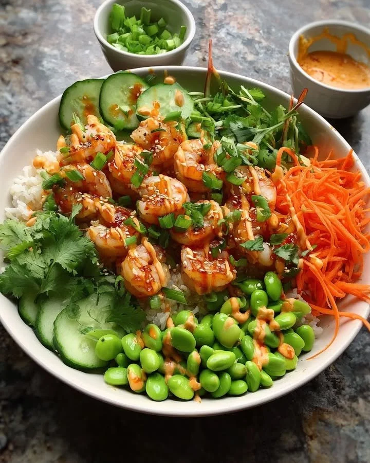 Delicious spicy shrimp rice bowl topped with fresh vegetables and herbs