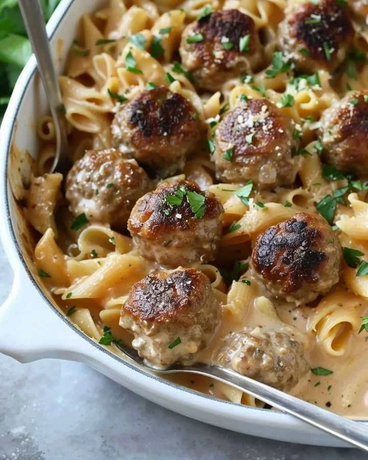 Delicious Swedish meatball pasta bake topped with melted cheese and fresh herbs