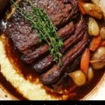 Slow-braised beef brisket with herb grits on a white plate