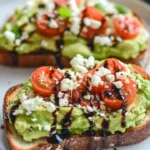 Plate of avocado toast topped with feta cheese and cherry tomatoes