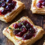 Cranberry Brie Puff Pastry Bites served on a rustic wooden board