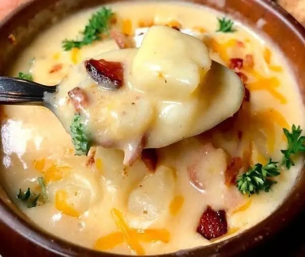 Bowl of creamy potato bacon soup topped with crispy bacon and herbs