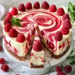 Elegant white chocolate raspberry swirl cheesecake topped with fresh raspberries.