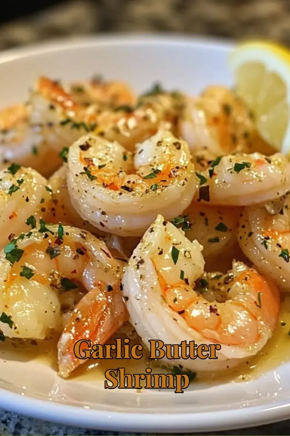 Plate of Garlic Butter Shrimp garnished with herbs and lemon.