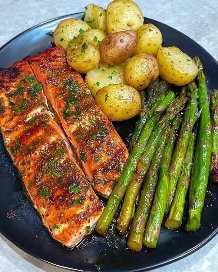 Garlic Herb Salmon served with asparagus and potatoes on a plate.