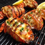 Plate of grilled lobster and shrimp garnished with herbs.