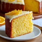 Slice of old-fashioned orange cake topped with orange zest and cream