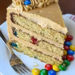 Delicious Peanut Butter M&M Cake topped with colorful M&Ms and creamy frosting.