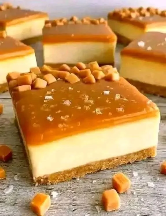 Delicious salted caramel cheesecake bars topped with caramel drizzle.