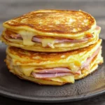 Salty pancakes topped with ham and cheese served on a plate