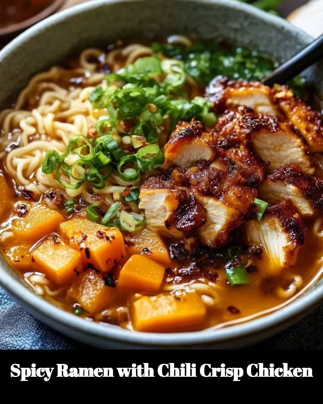 Bowl of spicy ramen topped with chili crisp chicken and garnished with green onions