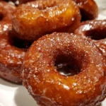 Delicious sweet potato donuts topped with glaze on a wooden table.