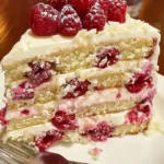 Delicious White Chocolate Raspberry Dream Cake topped with fresh raspberries.
