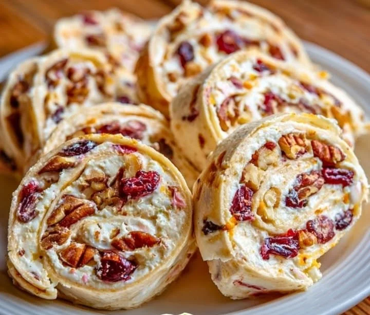 Cranberry-orange cream cheese pinwheels with pecans on a platter