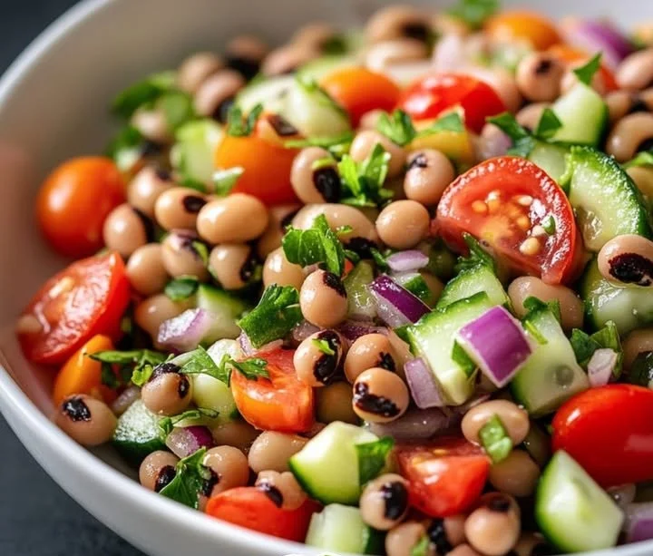 A colorful bowl of lucky black eyed pea salad with fresh ingredients and lemon dressing.