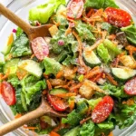 A classic house salad with fresh greens, tomatoes, cucumbers, and dressing.