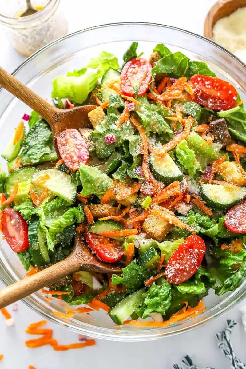 A classic house salad with fresh greens, tomatoes, cucumbers, and dressing.