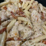 Creamy sun-dried tomato chicken pasta dish garnished with herbs