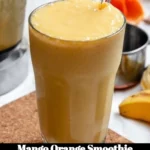 A refreshing mango orange smoothie in a glass garnished with fresh fruit.