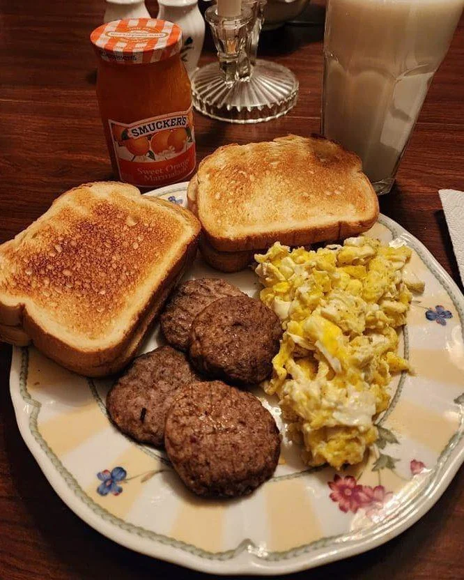 Scrambled eggs, sausage, and toast on a plate for a delicious breakfast