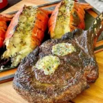 Plate of succulent steak and lobster served with fresh herbs and lemon