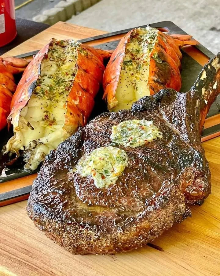 Plate of succulent steak and lobster served with fresh herbs and lemon