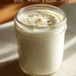 Creamy white garlic pizza sauce drizzled on freshly baked pizza