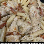 Creamy sun-dried tomato chicken pasta garnished with basil