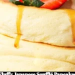 Fluffy Japanese soufflé pancakes stacked and drizzled with syrup.