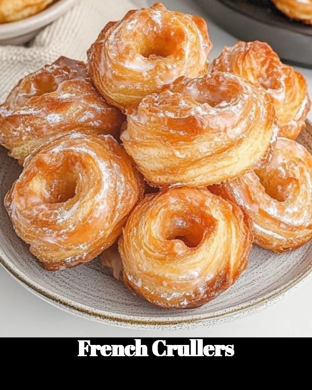 Freshly baked French Crullers on a plate, dusted with sugar.