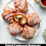 Golden fried croissant beignets dusted with powdered sugar on a plate