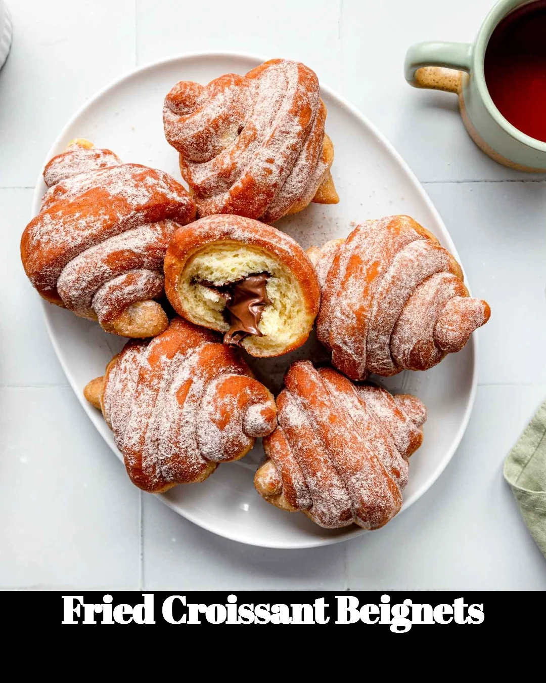 Golden fried croissant beignets dusted with powdered sugar on a plate