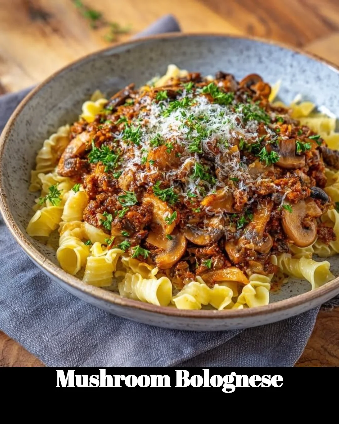 A bowl of Mushroom Bolognese pasta with fresh herbs and parmesan cheese.