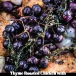 Thyme roasted chicken with caramelized shallots and grapes on a white plate.