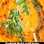 A bowl of Turkish red lentil soup garnished with herbs and spices