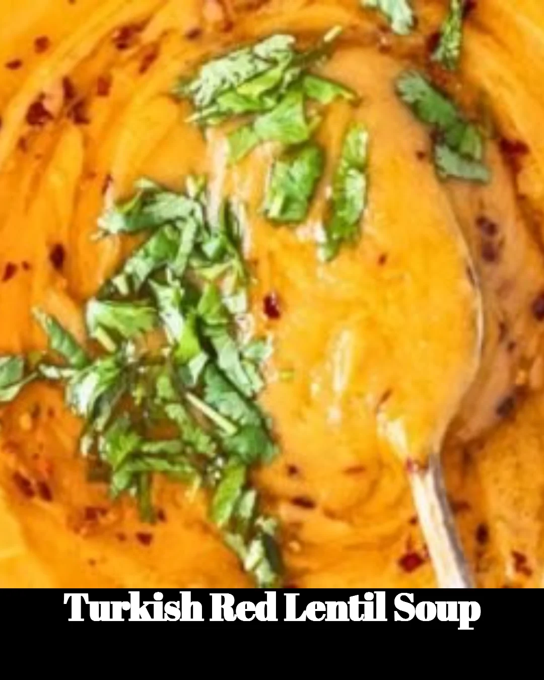 A bowl of Turkish red lentil soup garnished with herbs and spices