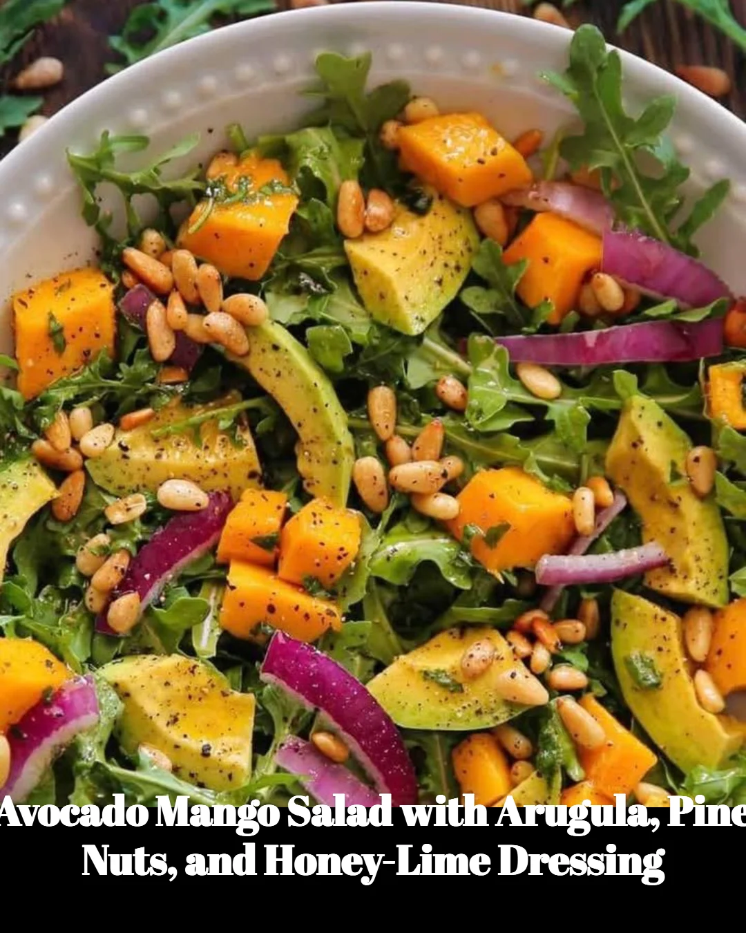 Avocado Mango Salad with arugula, pine nuts, and honey-lime dressing on a plate