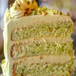 Slice of creamy pistachio cake decorated with nuts and frosting